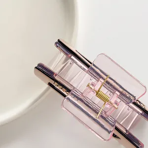 Pink translucent rectangular hair claw clip with rhinestones shown on ceramic tray