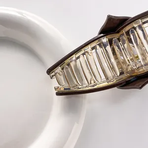 Detailed side view of a large acrylic hair claw clip with amber resin finish and metal spring