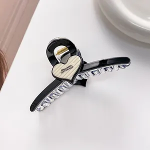 Detail of a black hair claw clip featuring a beige heart with Barrette La France text