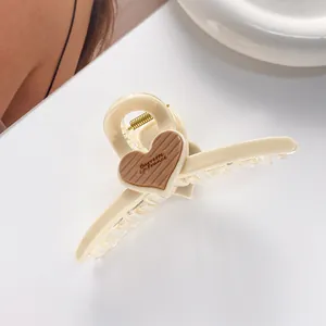 Detail of a cream acrylic hair claw with a coffee heart accent and metal spring