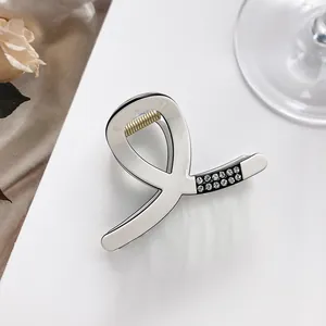 Close-up of cream white acrylic hair claw clip with sparkling rhinestones and metal spring
