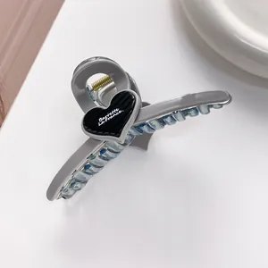Detail of grey heart-shaped claw clip with 'Barrette La France' text and golden spring