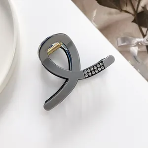 Detail view of small grey hair claw clip featuring sparkling rhinestones and gold spring
