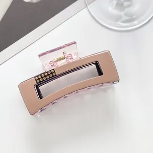 Detail of elegant rectangular hair claw clip with champagne finish and yellow rhinestones