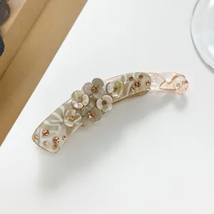 Macro detail of marble-textured banana hair clip with 3D resin flowers and amber rhinestones