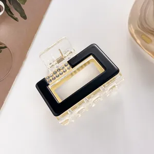 Detail of a rectangular hair claw clip with black and clear panels and tiny rhinestones