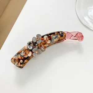 Macro detail of tortoiseshell banana hair clip with 3D resin flowers and inlaid rhinestones