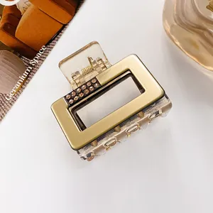 Macro shot of rectangular gold hair claw clip with amber rhinestones and resin finish