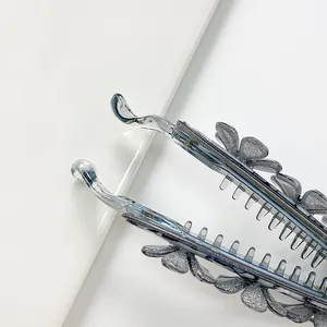 Dettaglio del fermaglio a banana grigio glitterato con fiore 3D e denti interni