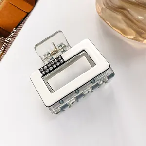 Close-up of a white rectangular hair claw clip with double-row rhinestone accents