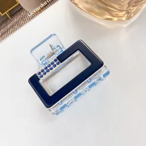 Detailed view of a small square hair claw clip with blue rhinestones and acrylic finish