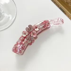 Detailed view of pink floral banana clip with resin petals and shimmering rhinestones