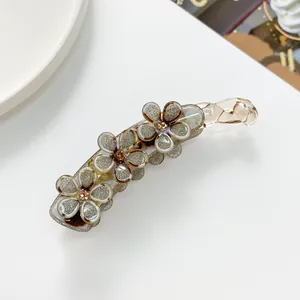 Dettaglio del fermaglio a banana in resina marrone con fiori glitterati e strass champagne