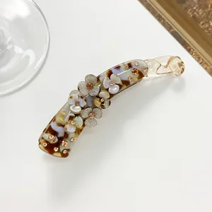 Detail view of tortoiseshell banana hair clip featuring floral patterns and rhinestones