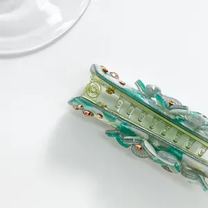 Detail of mint green marble acetate banana hair clip with crystal flowers and metal spring