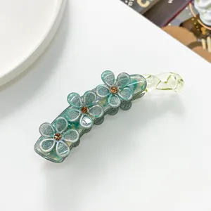 Dettaglio del fermaglio a banana con fiori glitterati verdi e strass ambra luminosi