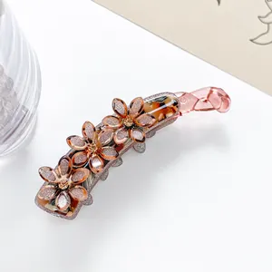 Makro-Detail der bernsteinfarbenen Bananenspange mit Glitzerblüten und kleinen Kristallen