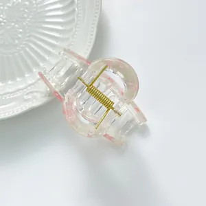 Pink marble pattern hair claw clip with golden metal spring on minimalist white background