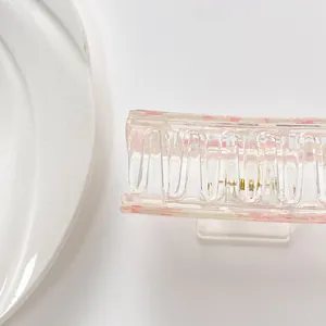 Detail of transparent acrylic hair claw with pink floral texture and gold metal spring