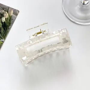 Detail of a pearl white rectangular hair claw clip with subtle checkered texture