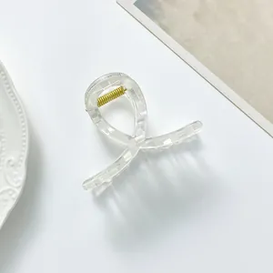 Detail of a transparent resin hair claw clip with white check pattern and gold spring