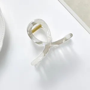 Close-up of a marbled white hair claw clip with golden spring on a ceramic plate