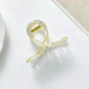 Detail of a marble textured cream hair claw clip with a strong gold metal spring