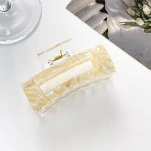 Detail of a large rectangular yellow marble pattern hair claw clip on a white background