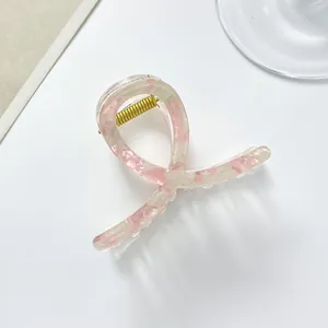 Macro detail of translucent pink floral hair claw clip with golden metal spring