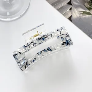 Close-up of a blue and white marble acrylic hair claw clip with a strong gold metal spring