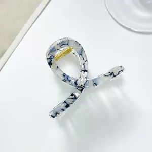 Detail shot of the marbled blue hair claw clip with golden metal spring and smooth finish