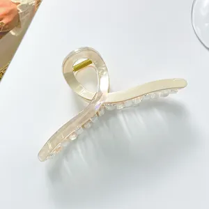 Macro detail of extra large cream hair claw clip with pearlescent finish and gold spring
