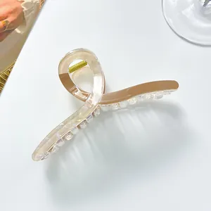 Close-up of extra-large amber and cream tortoiseshell hair claw clip with gold spring