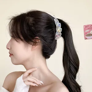 Iridescent leaf-shaped hair clip with gold metal base worn by model on long hair