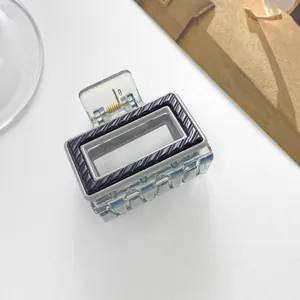 Detail of a rectangular hair claw clip with striped black texture on transparent blue base