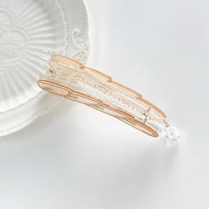 Macro detail of the translucent peach banana hair clip with secure grip teeth on a white plate