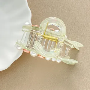 Dettaglio molletta per capelli con perle e strass rosa su base in resina verde