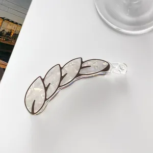 Detail of banana hair clip featuring white marble texture and brown leaf vein patterns