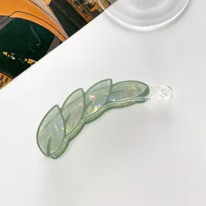 Macro detail of leaf-shaped banana hair clip in iridescent green acrylic finish