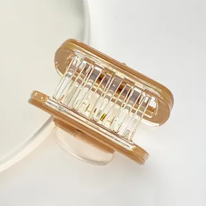Close-up van een vierkante amberkleurige haarklem met transparant frame en veer