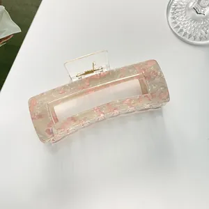 Detailed macro view of a large pink marble acetate hair claw clip with golden metal spring
