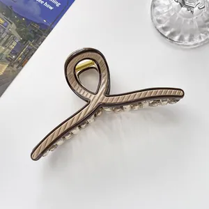 Nahaufnahme der 13cm gestreiften Haarklammer mit starker Goldmetallfeder auf dem Tisch