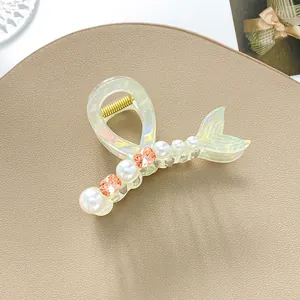 Dettaglio del fermaglio per capelli a sirena iridescente con perle e strass arancioni