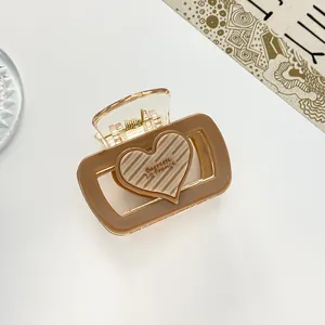 Detail van een bruine doorzichtige haarklem met een gestreept hart en merktekst