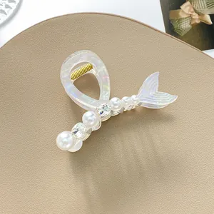 Dettaglio del fermaglio a coda di sirena cangiante con perle e strass su vassoio
