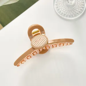 Detailansicht einer 11cm Haarklammer aus karamellfarbenem Harz mit goldener Feder