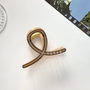 Détail d'une pince à cheveux dorée champagne avec touches marron et cinq strass brillants
