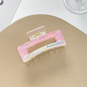 Close-up of iridescent pink gradient hair claw with gold spring and Barrette text