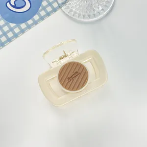Detail view of cream hair claw clip with brown Barrette La France circular disc detail