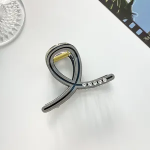Détail d'une mini pince à cheveux grise avec strass et ressort doré sur fond blanc